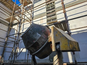 Betoniarka na tle murów i rusztowania