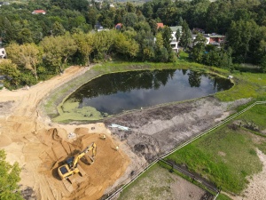 koparka podczas prac i zbiornik retencyjny wypełniony wodą w tle